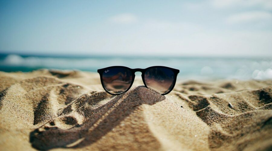 black Ray-Ban Wayfarer sunglasses on beach sand